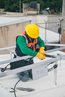 instalador de placa solar em cima de um telhado realizando a instalação de uma placa solar.