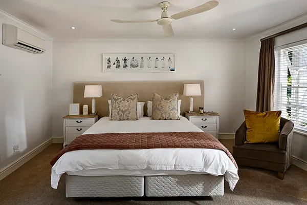 quarto de casal com cama ao centro, chao amadeirado ao lado esquerdo um ar condicionado.